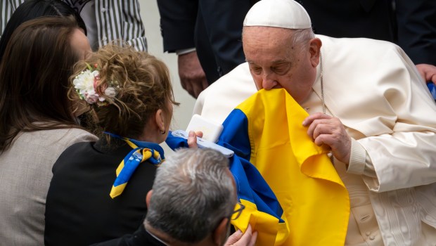 Pope Francis kisses the Ukrainian flag