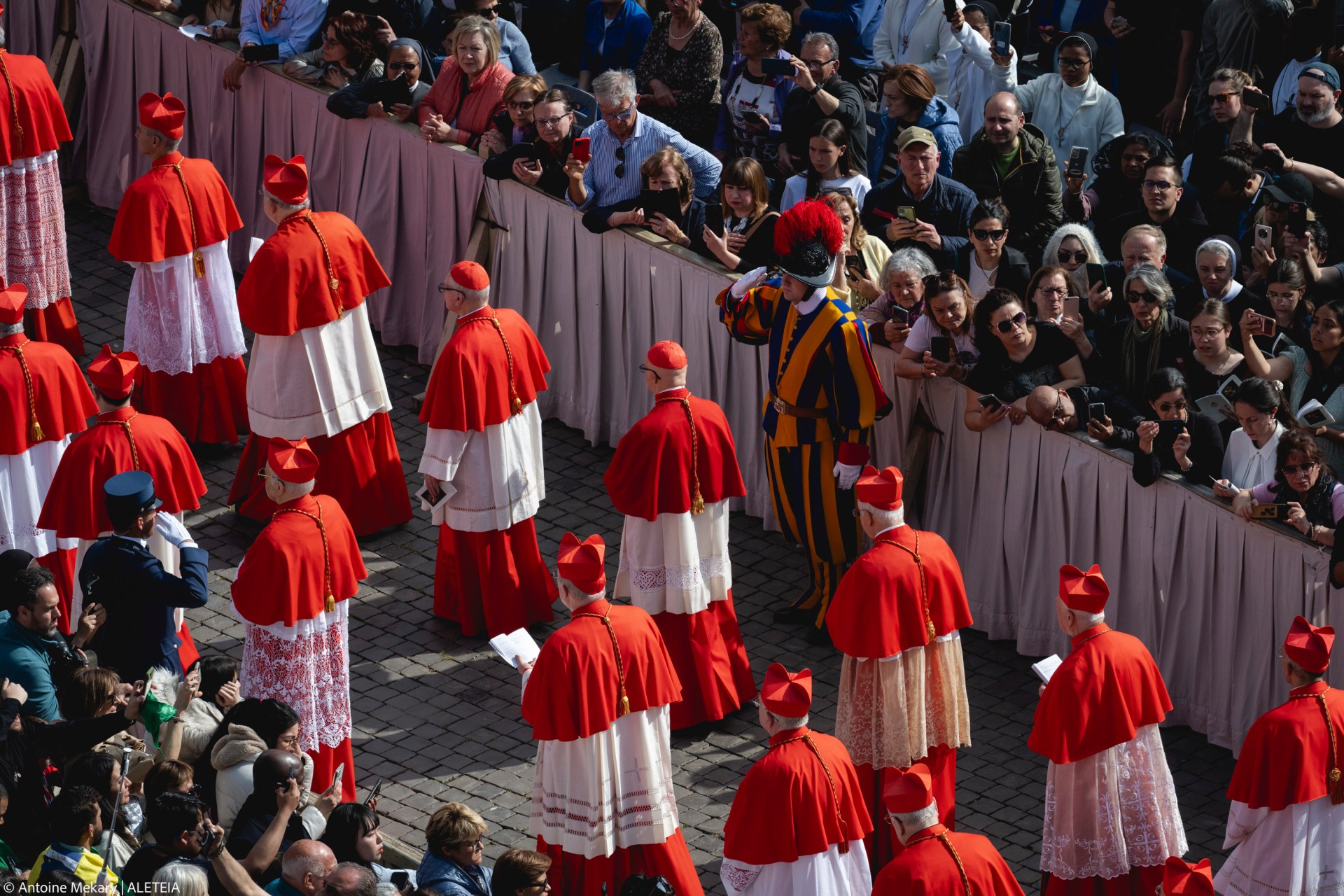 Members of the clergy march next to attendees prior to the arrival of the coffin of the late Pope, set to be transported from the chapel of Santa Marta to St Peter's Basilica, following the Pope's death, in the Vatican on April 23, 2025.