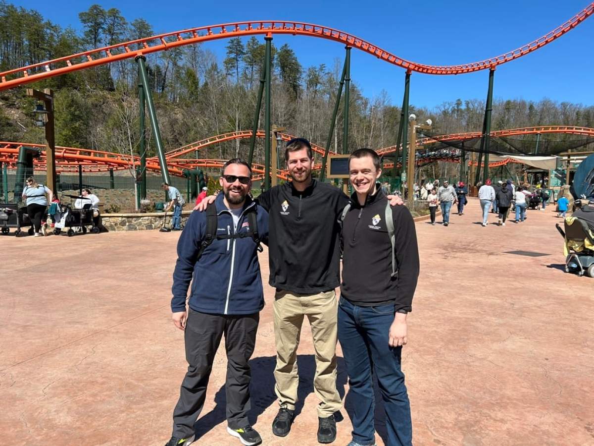 Three priests in front of a roller coaster