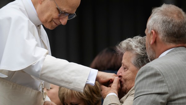 A woman kisses the hand Pope Leo XIV at the end of his first weekly general audience at St Peter's Square in The Vatican on May 21, 2025