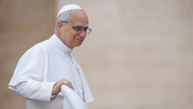 A woman kisses the hand Pope Leo XIV at the end of his first weekly general audience at St Peter's Square in The Vatican on May 21, 2025