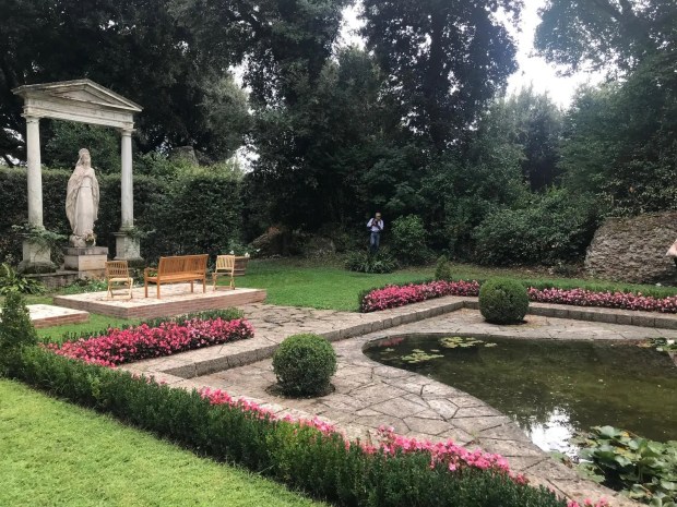 A statue of Mary presides over a clearing with a man-made pond at Borgo Laudati si' in Castel Gandolfo.