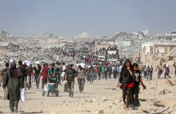 Palestinians carry flour and food aid they received at the Zikim crossing in the central Gaza Strip, August 8, 2025