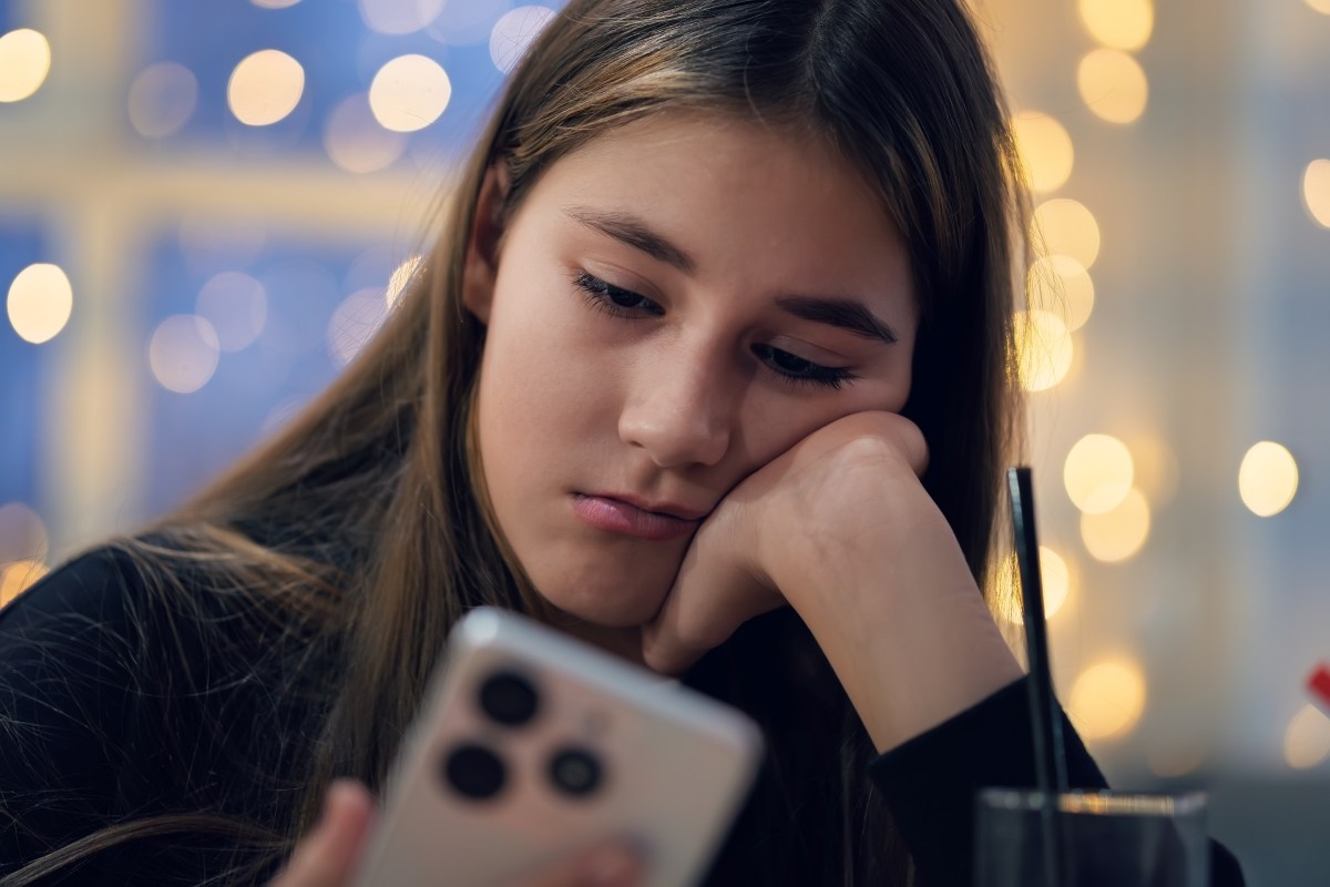 A teenage girl holds a smartphone in her hands